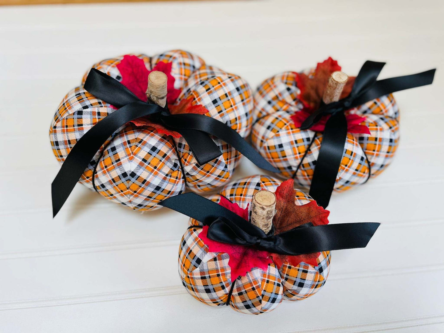 Introducing our set of 3 fabric pumpkins, available in large, medium, and small sizes. These pumpkins are made from a unique black, orange, and white plaid fabric,