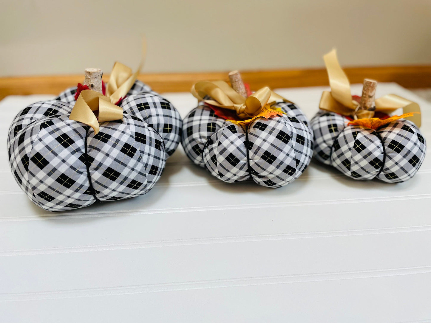 Introducing our set of 3 fabric pumpkins, available in large, medium, and small sizes. These pumpkins are made from a unique black, white and gold plaid fabric, ad