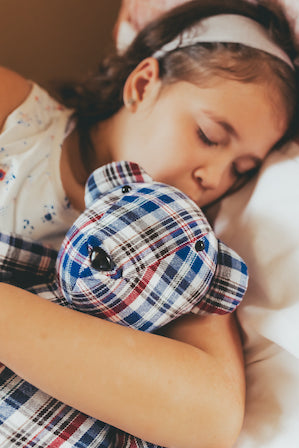 a little girl hugging a memory bear. Made from a plaid shirt