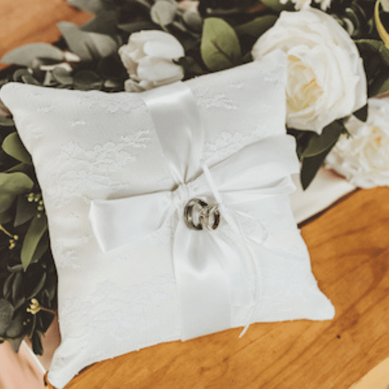 Beautiful ring pillow will be the perfect addition to your wedding. This simple but elegant ring pillow is made with white satin. Features a lace overlay and satin r