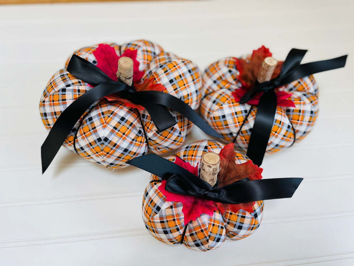  
Introducing our set of 3 fabric pumpkins, available in large, medium, and small sizes. These pumpkins are made from a unique black, orange, and white plaid fabric,