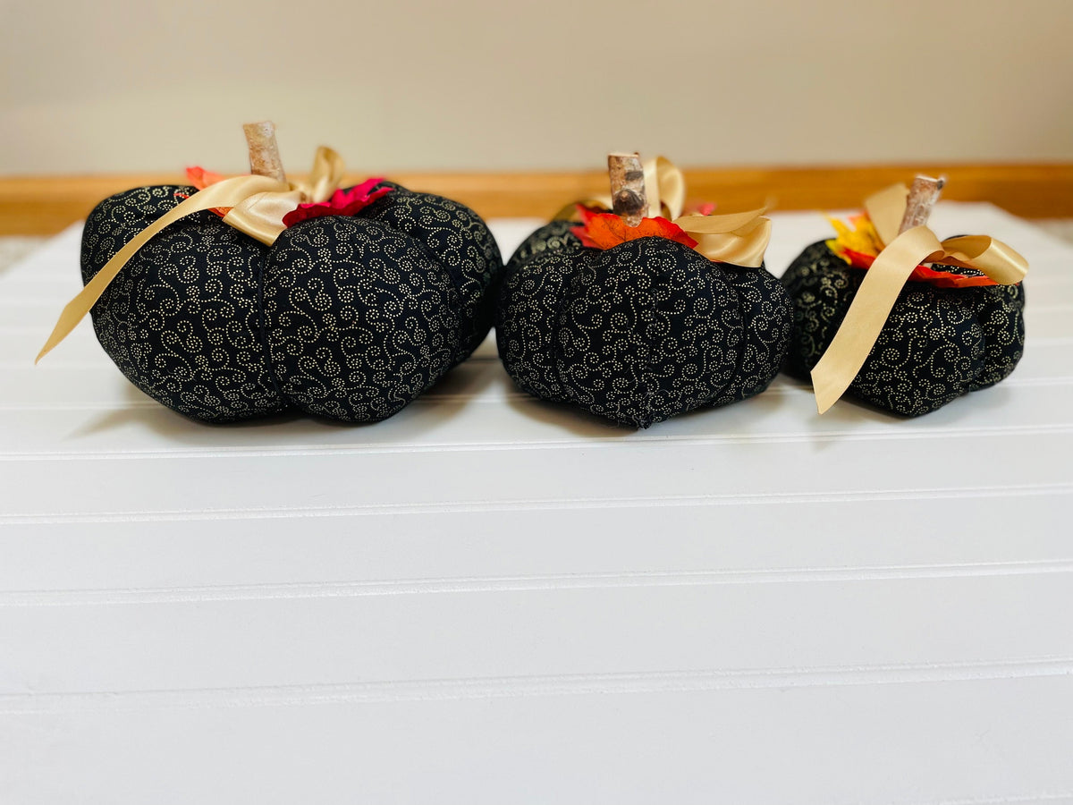 Introducing our set of 3 fabric pumpkins, available in large, medium, and small sizes. These pumpkins are made from a unique black and gold swirled fabric, adding a 